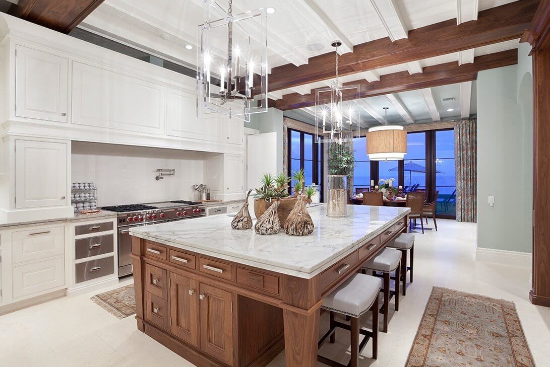 traditional kitchen marble island with wood cabinets and exposed wooden beams