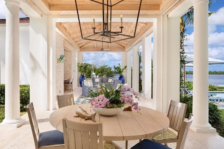 Wooden table on an open, lakefront terrace with a pool off to the side.