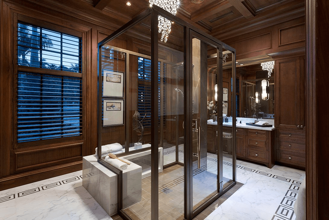 A luxurious bathroom in Palm Beach with a chandelier, mirror sconces, and beautiful lighting acting as accessories.